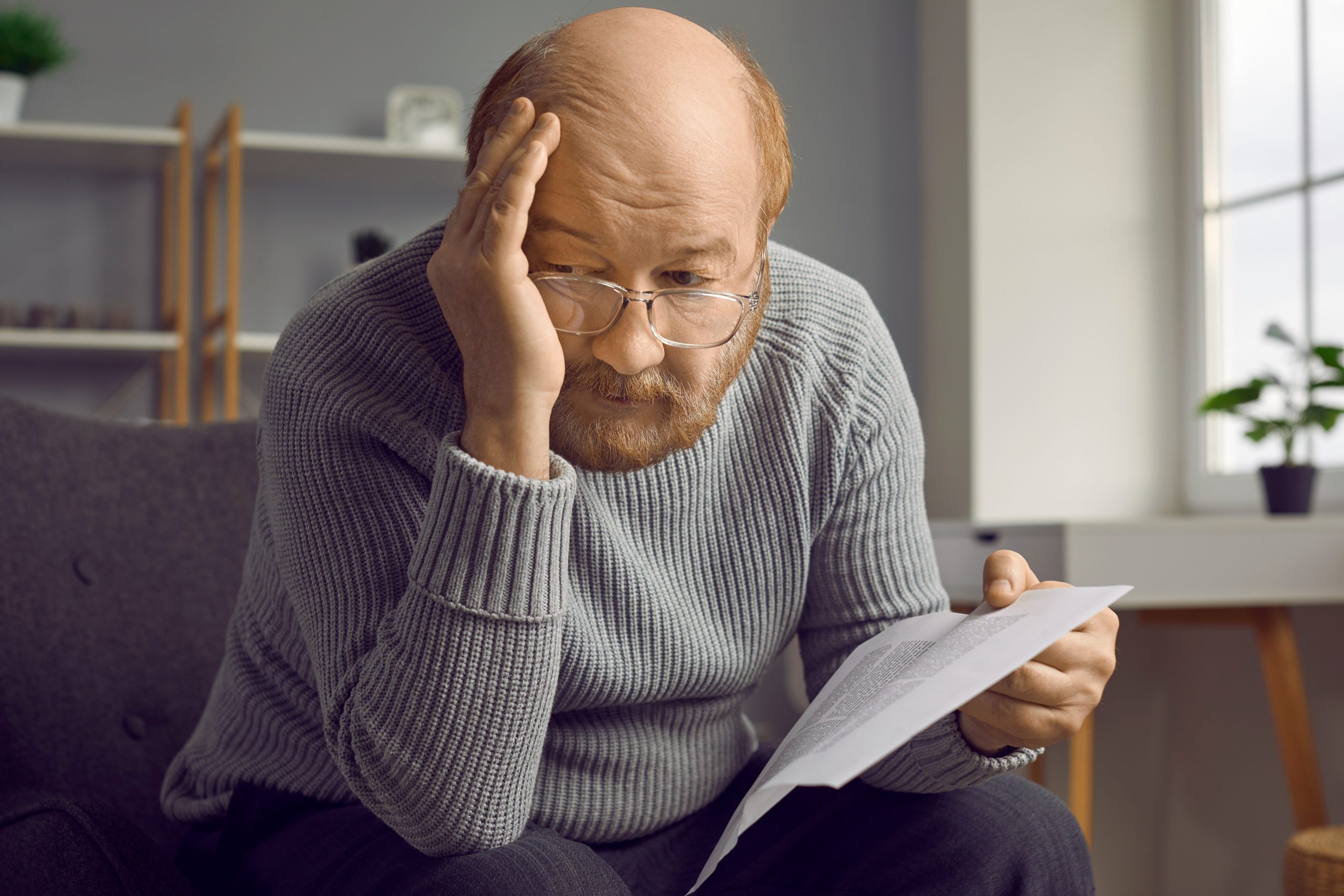 A stressed older man, looking at a document.
